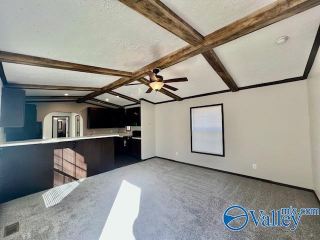 interior space featuring vaulted ceiling with beams, ceiling fan, carpet, and a textured ceiling