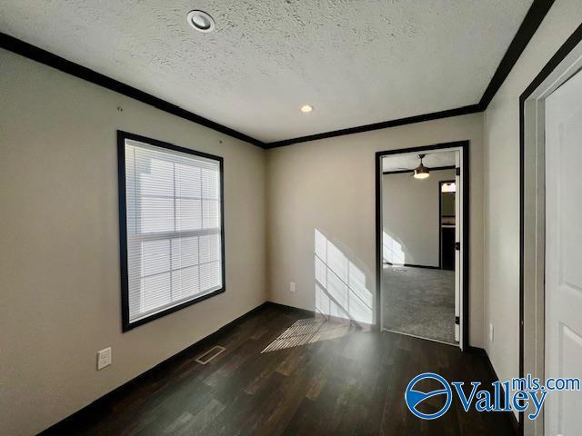 empty room with crown molding, dark hardwood / wood-style flooring, and a textured ceiling