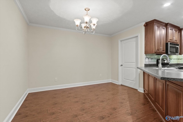 kitchen with appliances with stainless steel finishes, dark hardwood / wood-style flooring, sink, an inviting chandelier, and backsplash