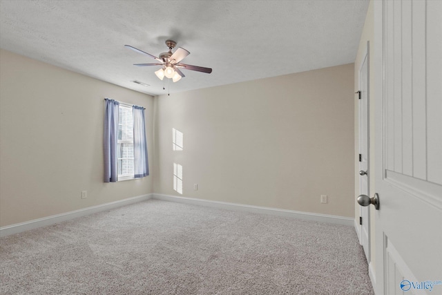 spare room featuring light colored carpet, ceiling fan, and a textured ceiling