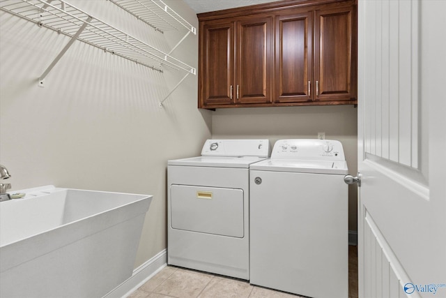 clothes washing area with sink, cabinets, washing machine and clothes dryer, and light tile patterned floors