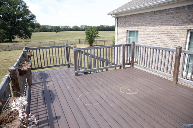 deck with a fenced backyard, a lawn, and a rural view