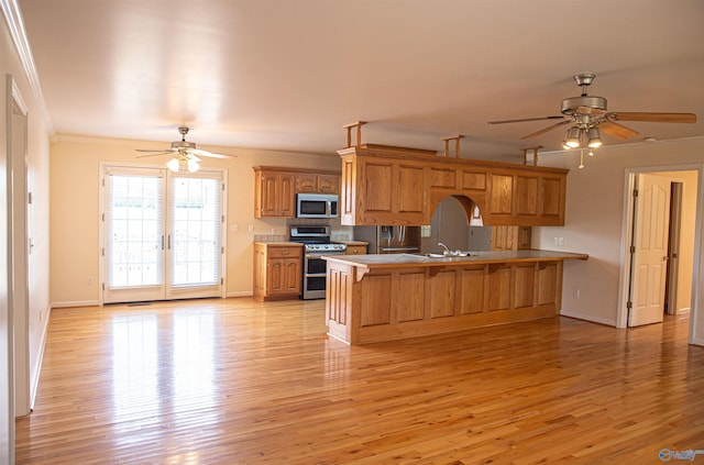 kitchen with brown cabinetry, appliances with stainless steel finishes, a breakfast bar, a peninsula, and crown molding