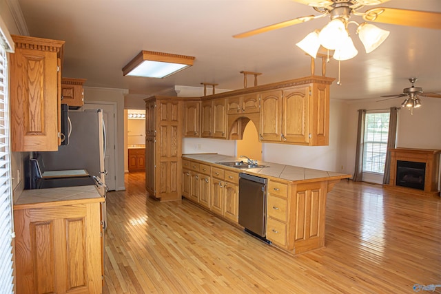 kitchen with tile countertops, light wood-type flooring, a sink, and dishwasher