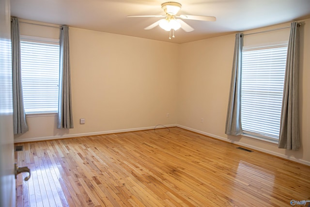 unfurnished room with baseboards, light wood-style flooring, visible vents, and a ceiling fan