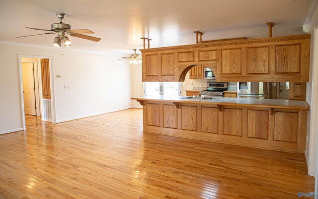 kitchen featuring light wood finished floors, ornamental molding, a kitchen breakfast bar, a peninsula, and stainless steel appliances