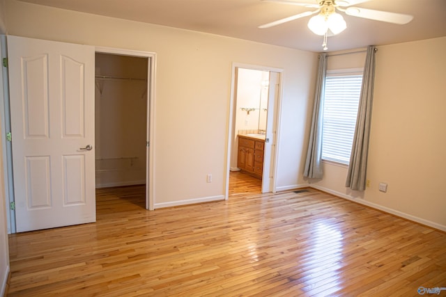 unfurnished bedroom with light wood-style floors, baseboards, a walk in closet, and a closet