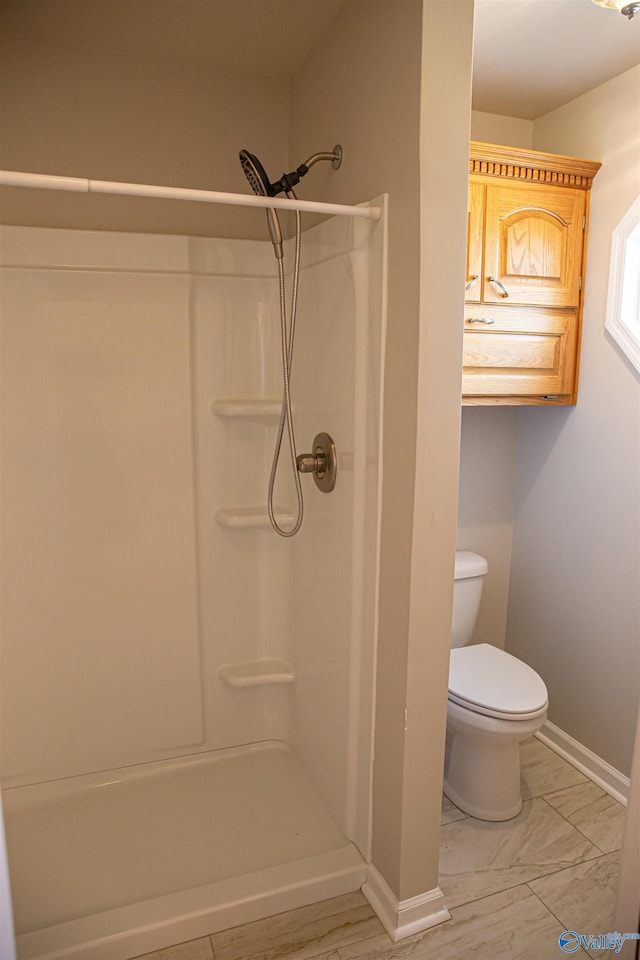 full bath featuring toilet, baseboards, and walk in shower