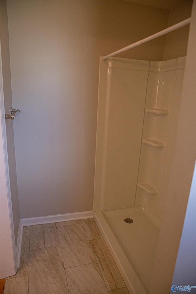 full bathroom with marble finish floor, baseboards, and walk in shower