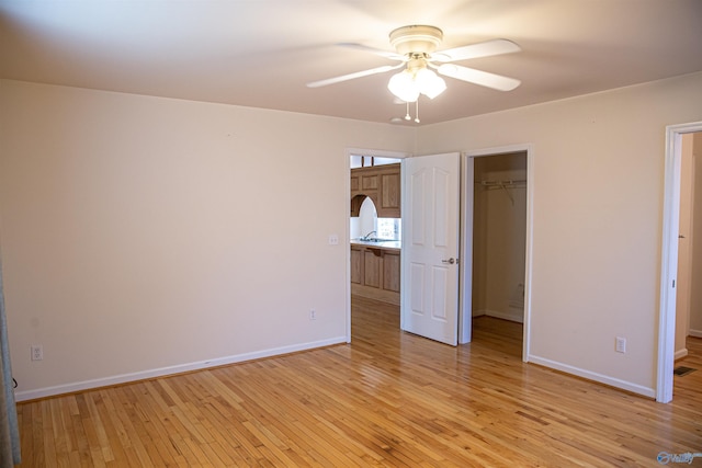 unfurnished bedroom with a spacious closet, a closet, light wood-type flooring, and baseboards