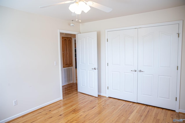 unfurnished bedroom featuring light wood-style floors, a closet, baseboards, and a ceiling fan