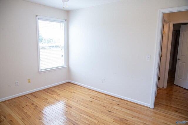 unfurnished room with a healthy amount of sunlight, light wood-style flooring, and baseboards