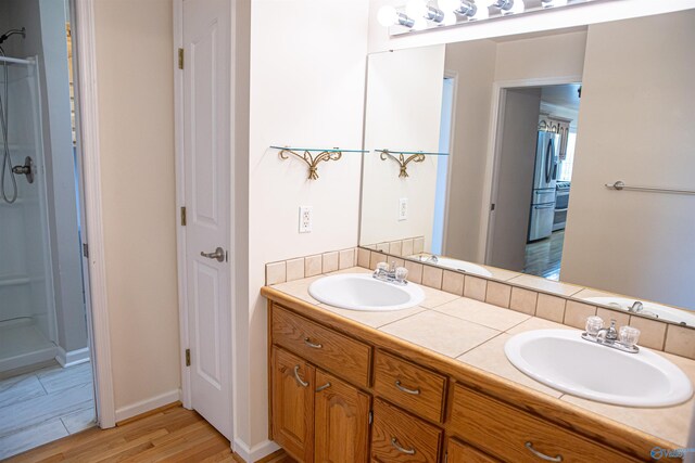 bathroom featuring double vanity, a sink, and walk in shower