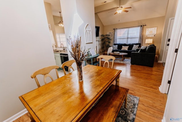 dining area featuring vaulted ceiling, ceiling fan, sink, and light hardwood / wood-style flooring