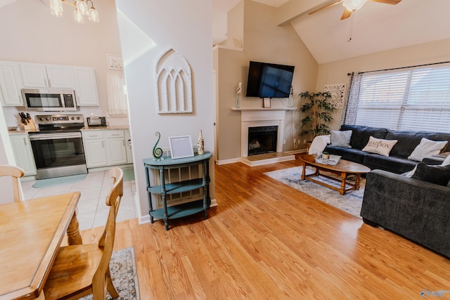 living room featuring beamed ceiling, ceiling fan, light hardwood / wood-style floors, and high vaulted ceiling