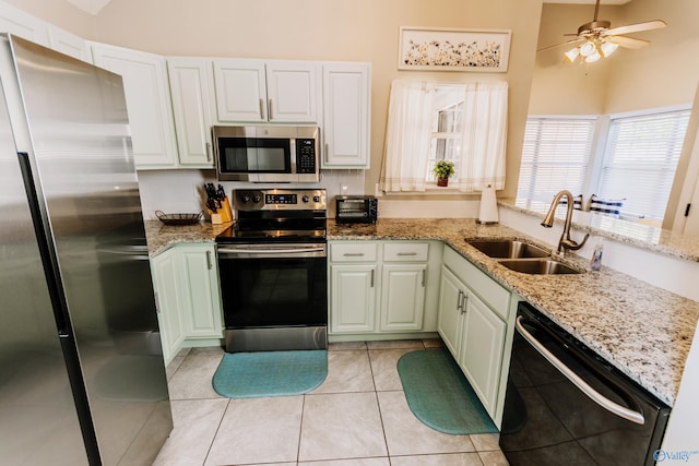 kitchen featuring light tile patterned flooring, sink, white cabinets, stainless steel appliances, and light stone countertops