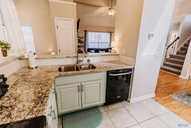 kitchen with dishwasher, sink, light tile patterned floors, light stone counters, and kitchen peninsula