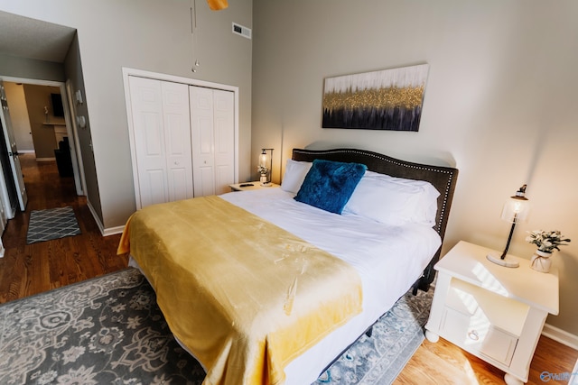 bedroom featuring hardwood / wood-style floors, a closet, and a high ceiling