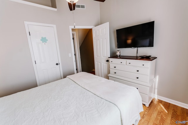 bedroom with a towering ceiling, light hardwood / wood-style floors, and ceiling fan