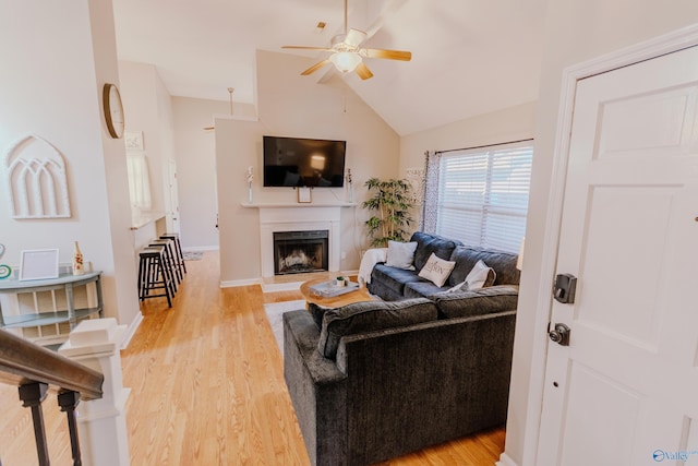 living room featuring vaulted ceiling, ceiling fan, and light wood-type flooring