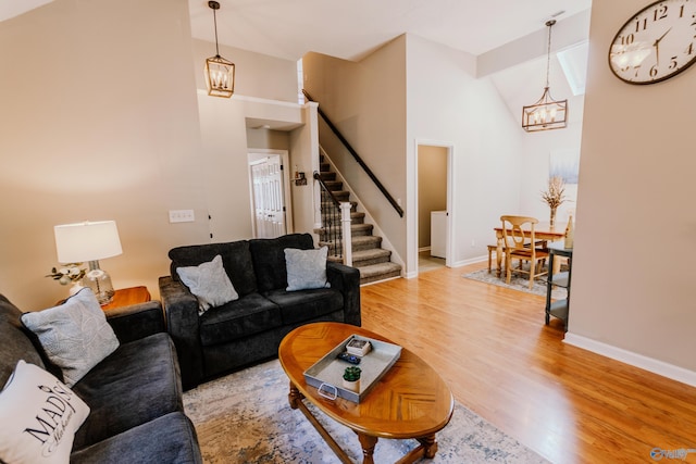 living room with a chandelier, high vaulted ceiling, and light hardwood / wood-style flooring