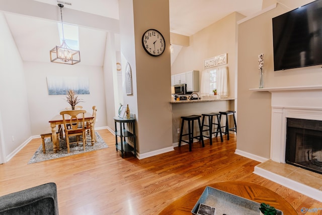 living room featuring a notable chandelier, a tile fireplace, and light wood-type flooring