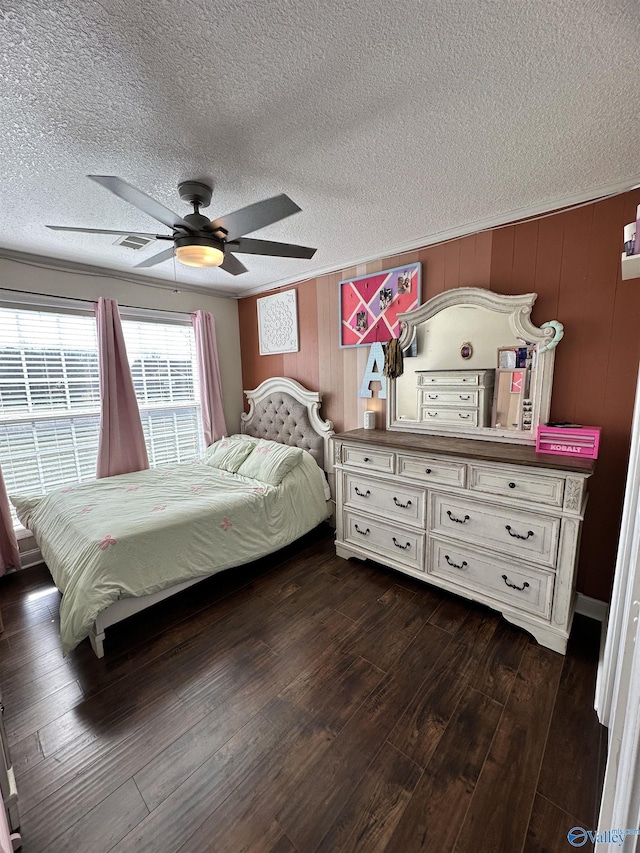 bedroom with ceiling fan, dark wood-type flooring, a textured ceiling, and wooden walls