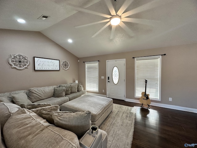 living room with dark wood-type flooring, a textured ceiling, plenty of natural light, and vaulted ceiling