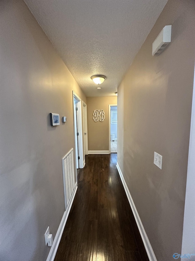 hallway featuring dark wood-type flooring and a textured ceiling