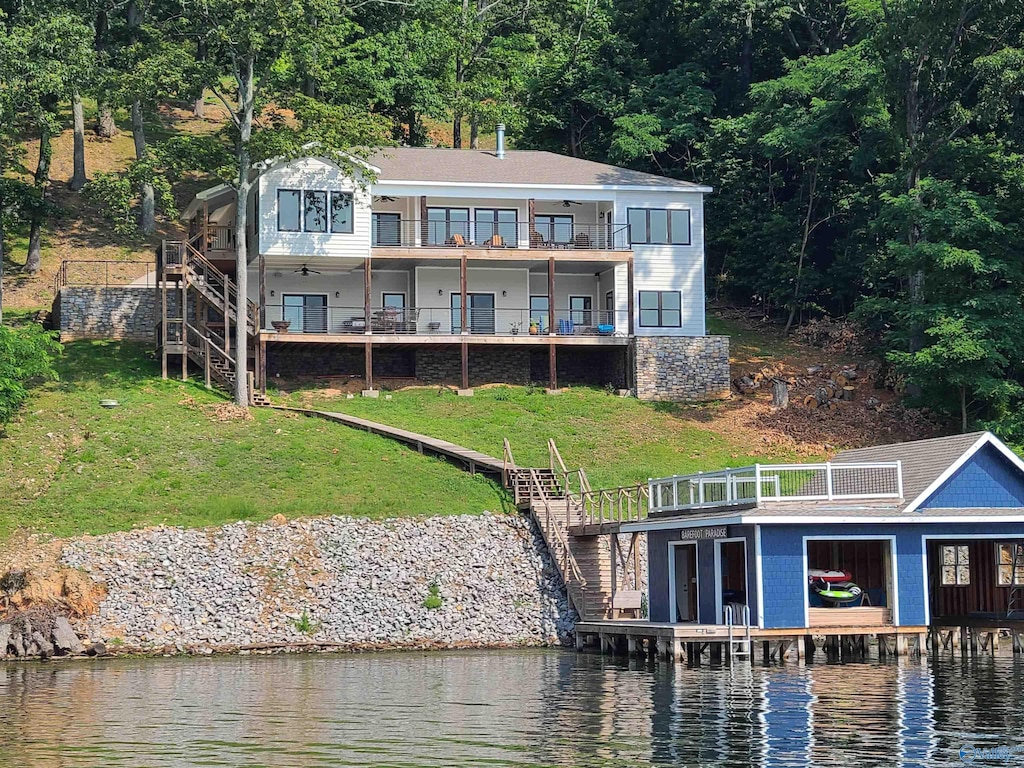 back of property featuring a yard, a water view, and a balcony