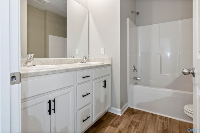 full bathroom featuring washtub / shower combination, dual bowl vanity, toilet, and hardwood / wood-style floors