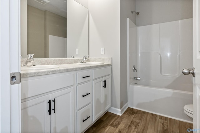 bathroom with double vanity, shower / washtub combination, wood finished floors, and a sink