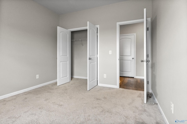 unfurnished bedroom with baseboards, carpet floors, and a closet