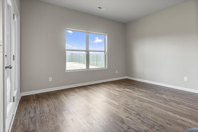 unfurnished room with dark wood-style floors, visible vents, and baseboards