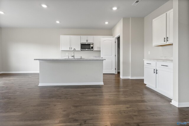 kitchen featuring white cabinetry, dark hardwood / wood-style flooring, sink, and a center island with sink