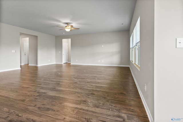 unfurnished room featuring baseboards, dark wood-type flooring, and ceiling fan