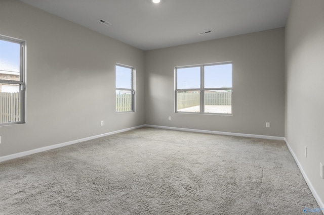 empty room featuring carpet flooring, visible vents, and baseboards