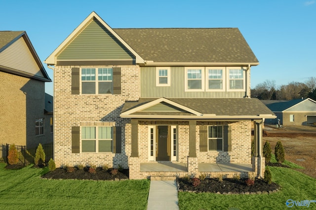 view of front of home with board and batten siding, brick siding, a patio, and a front lawn