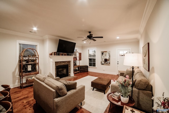 living room featuring a stone fireplace, ceiling fan, hardwood / wood-style floors, and ornamental molding