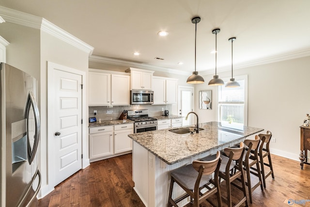 kitchen featuring white cabinets, a kitchen island with sink, sink, and appliances with stainless steel finishes