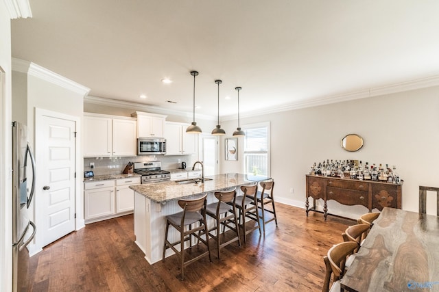 kitchen featuring light stone countertops, sink, hanging light fixtures, stainless steel appliances, and a kitchen island with sink