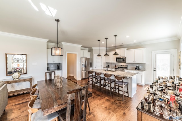 dining area with ornamental molding, dark wood-type flooring, and sink