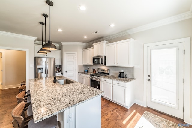 kitchen featuring white cabinets, appliances with stainless steel finishes, a center island with sink, and sink