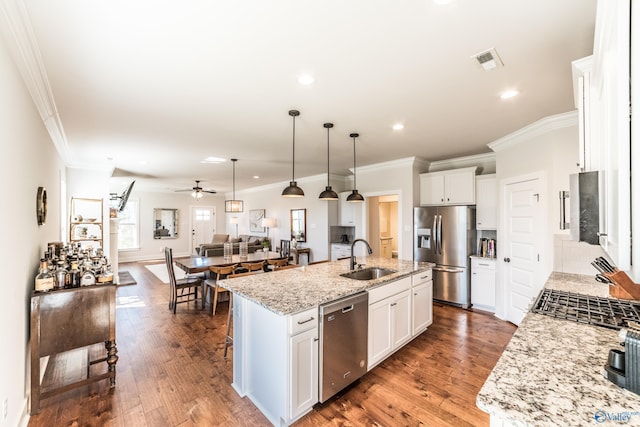 kitchen featuring a center island with sink, light stone counters, white cabinetry, and stainless steel appliances