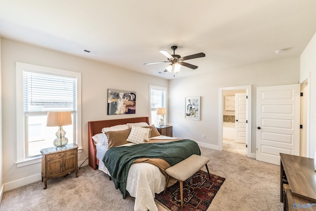 bedroom featuring ceiling fan, light carpet, connected bathroom, and multiple windows