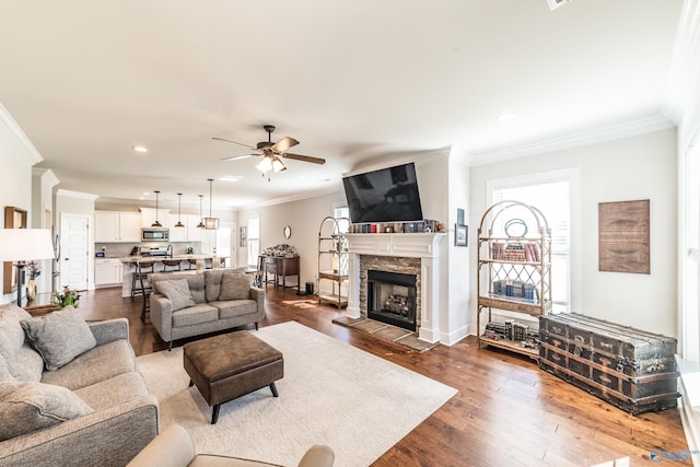 living room with a fireplace, hardwood / wood-style flooring, ceiling fan, and crown molding