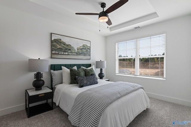 bedroom featuring a raised ceiling, ceiling fan, and carpet flooring