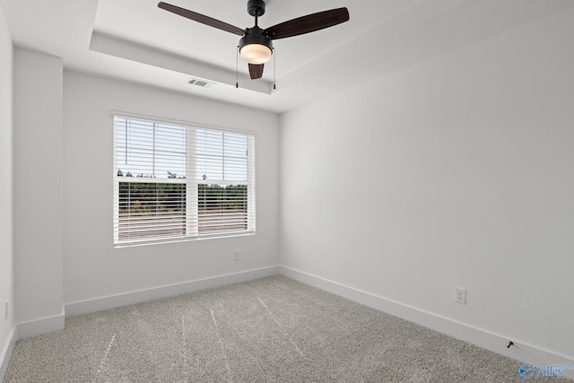 spare room featuring carpet, ceiling fan, and a tray ceiling