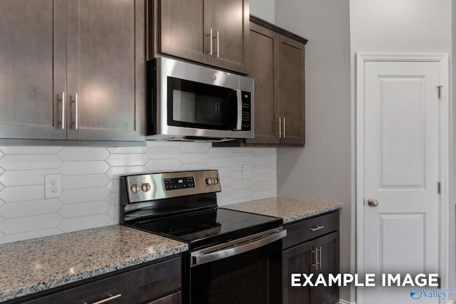 kitchen with appliances with stainless steel finishes, tasteful backsplash, light stone counters, and dark brown cabinets