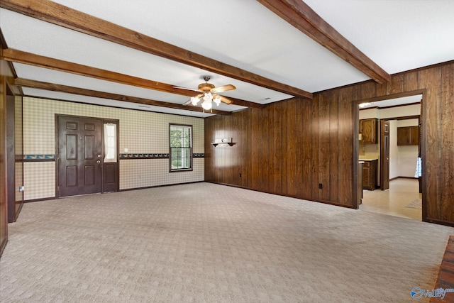 708 Apache St NW, Hartselle, AL 35640 - unfurnished living room featuring a ceiling fan, beamed ceiling, carpet, wooden walls, and baseboards